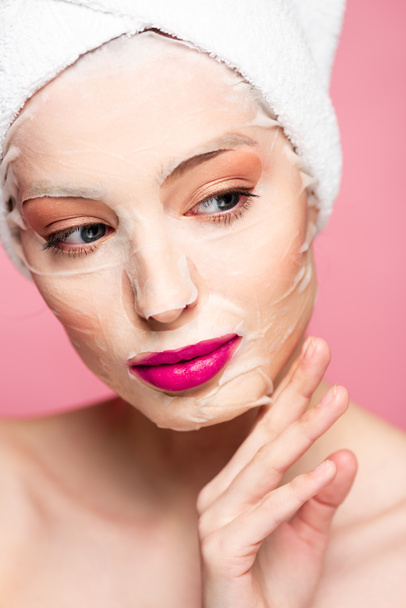 naked girl in moisturizing face mask looking away isolated on pink  - Photo, Image