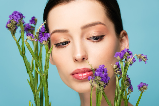 beautiful woman looking at limonium flowers isolated on blue  - Foto, immagini