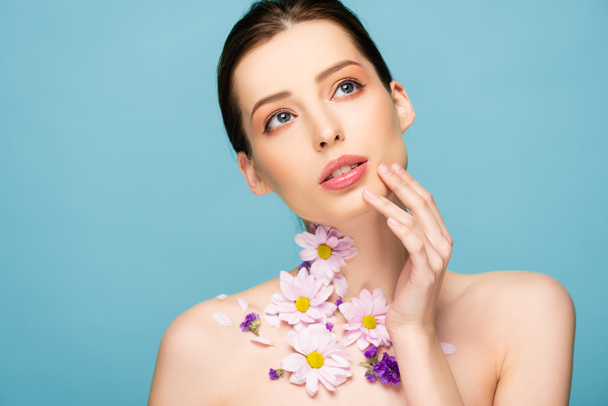naked young woman with flowers on neck touch face isolated on blue  - Fotoğraf, Görsel