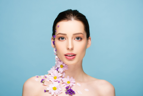 naked young woman with flowers looking at camera isolated on blue  - Foto, Imagem