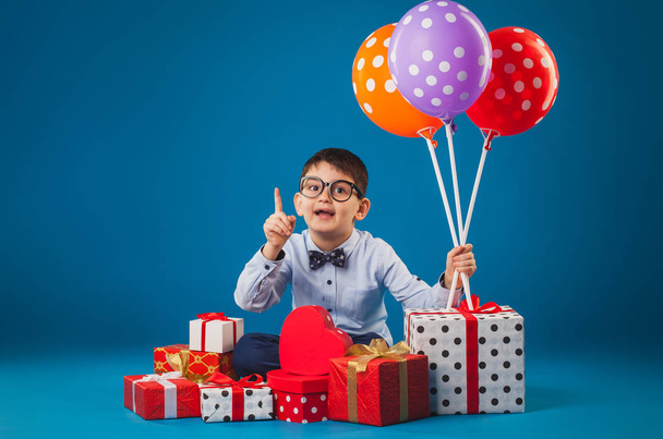 Cute kid with gifts on the blue background - Фото, зображення