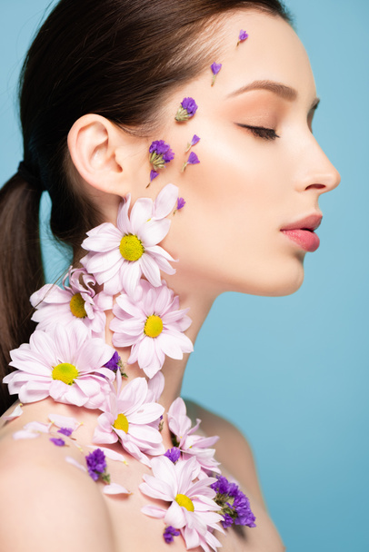 side view of pretty woman with blossoming flowers on body isolated on blue  - Fotoğraf, Görsel