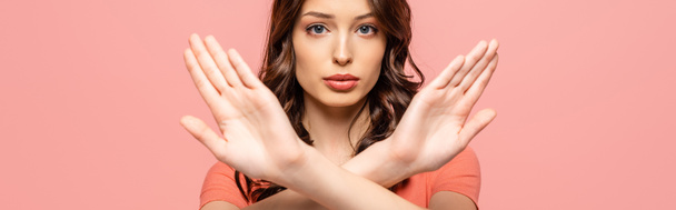 panoramic shot of serious young woman showing stop gesture while looking at camera isolated on pink - Foto, Bild