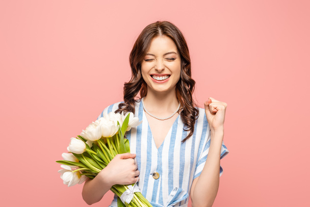 excited girl showing yeah gesture while holding bouquet of white tulips isolated on pink - Фото, зображення