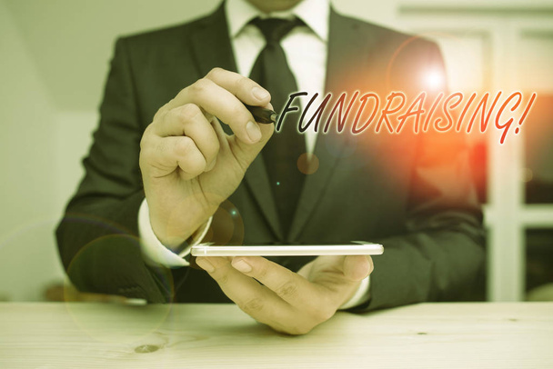 Text sign showing Fundraising. Conceptual photo seeking to generate financial support for charity or cause Male human wear formal clothes present presentation use hi tech smartphone. - Photo, Image