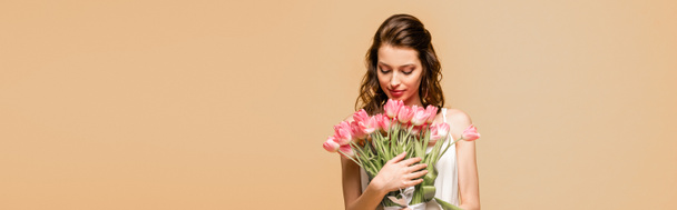 plano panorámico de chica feliz sosteniendo tulipanes rosados aislados en rosa
 - Foto, imagen