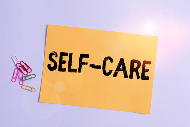 Pisanie tekstu Self Care. Biznesowe zdjęcie pokazujące praktykę podejmowania działań w celu poprawy własnego zdrowia Zwykły karton i sprzęt do pisania umieszczony powyżej pastelowego tła kolorów - Zdjęcie, obraz
