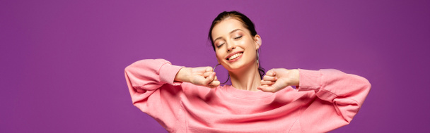 panoramiczne ujęcie szczęśliwej dziewczyny rozciągającej się z zamkniętymi oczami na fioletowym - Zdjęcie, obraz