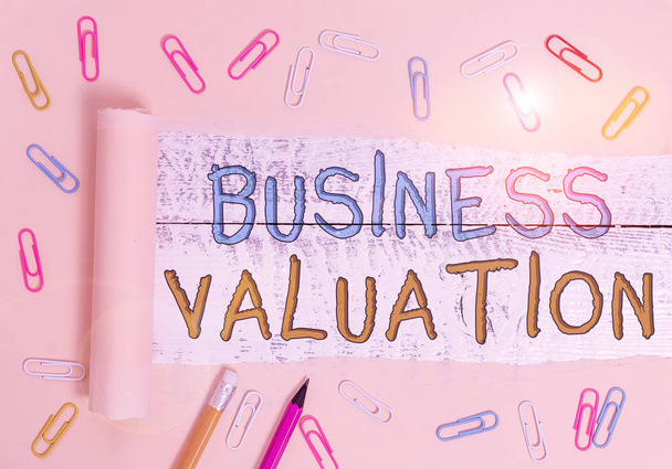 Text sign showing Business Valuation. Business photo showcasing determining the economic value of a whole business Stationary and torn cardboard placed above a wooden classic table backdrop - Photo, Image