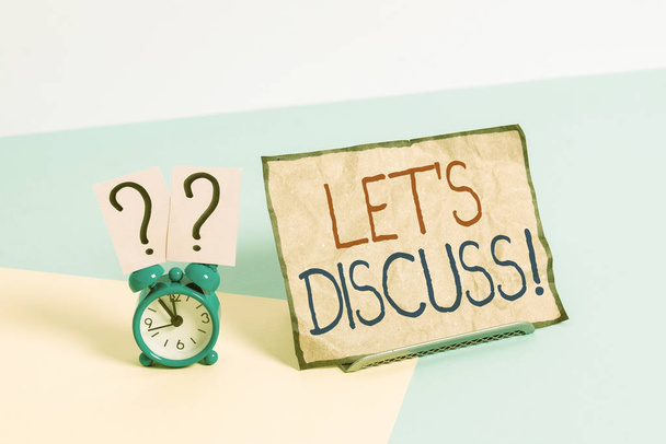 Writing note showing Let S Discuss. Business concept for asking someone to talk about something with demonstrating or showing Alarm clock beside a Paper sheet placed on pastel backdrop - Photo, Image