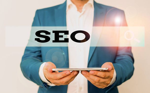 Word writing text Seo. Business photo showcasing incredibly effective way to market your near business online Man in the blue suite and white shirt holds mobile phone in the hand - Photo, Image