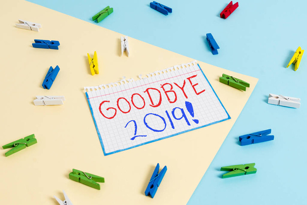 Writing note showing Good Bye 2019. Business concept for express good wishes when separing or at the end of past year Colored clothespin χάρτινη υπενθύμιση με κίτρινο μπλε φόντο - Φωτογραφία, εικόνα
