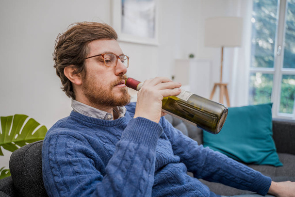 Portrait of man with alcohol drink sitting on sofa at home - Fotografie, Obrázek