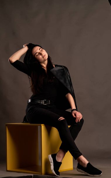 young brunette woman in stylish clothes posing in dark studio   - Foto, afbeelding