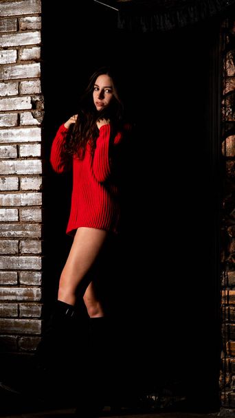 Mooie sexy naakte vrouw in rode trui op donkere achtergrond    - Foto, afbeelding