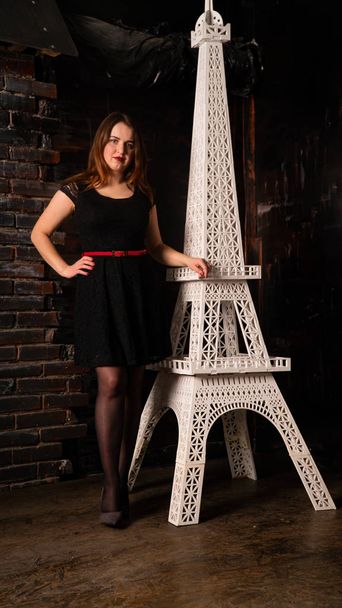 jolie femme en robe noire posant près de la tour Eiffel décorative  - Photo, image