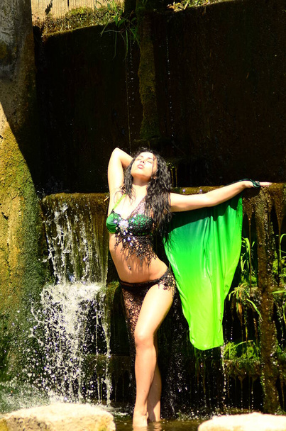 Young brunette model posing against a waterfall - Photo, Image