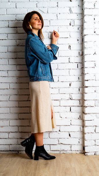 brunette fille dans une veste verte et soutien-gorge se tient près du mur de briques blanches
. - Photo, image