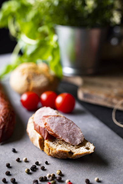 Sandwich with traditional homemade smoked sausage on stony countertop. - Foto, Imagen
