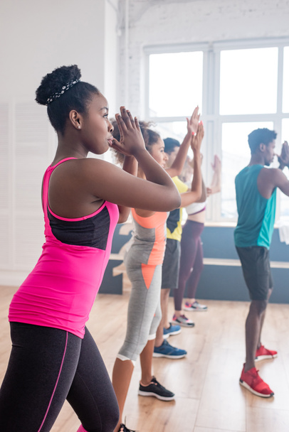 Selective focus of multiethnic dancers performing zumba with african american trainer in studio - Photo, image