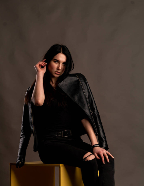 young brunette woman in stylish clothes posing in dark studio   - Foto, imagen