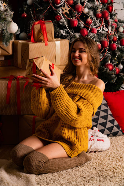 Noel süslemeli stüdyoda şöminenin yanında poz veren güzel esmer genç bir kadın.  - Fotoğraf, Görsel