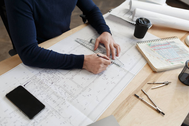 Architect working in office with blueprints.Engineer inspect architectural plan, sketching a construction project.Portrait of handsome bearded man sitting at workplace. Business construction concept - Фото, изображение
