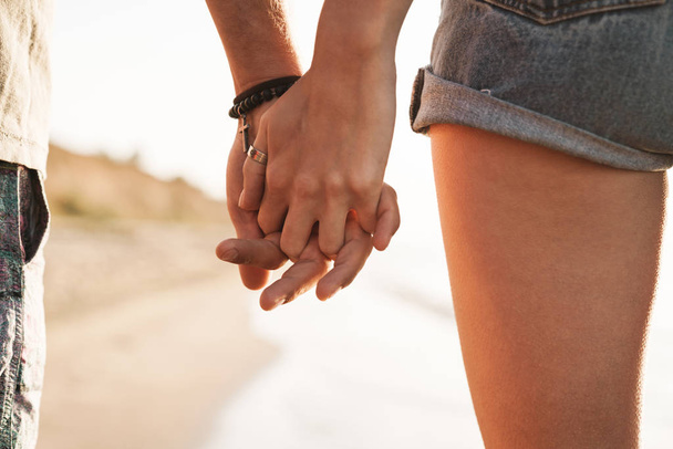 Καλλιεργημένη φωτογραφία του ρομαντικού ζευγαριού που κρατιέται χέρι-χέρι - Φωτογραφία, εικόνα