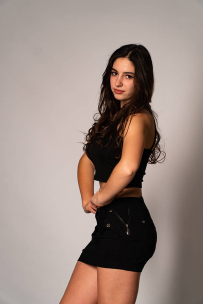 Beautiful woman with dark hair in black clothes posing on light studio background  - Foto, Imagen