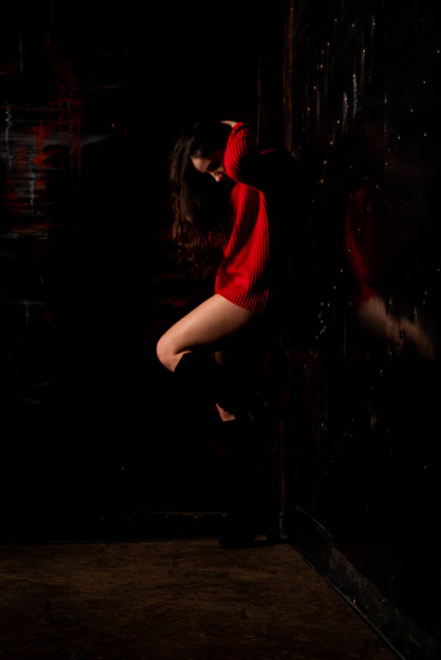 Beautiful sexy nude woman in red sweater on dark background    - Фото, зображення