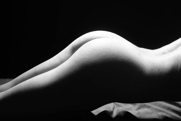 Black and White Beautiful woman body. Fashion art studio portrait of elegant naked lady with shadow on her. Female stomach isolated on black background. Erotic pose low key shoot. - Foto, immagini
