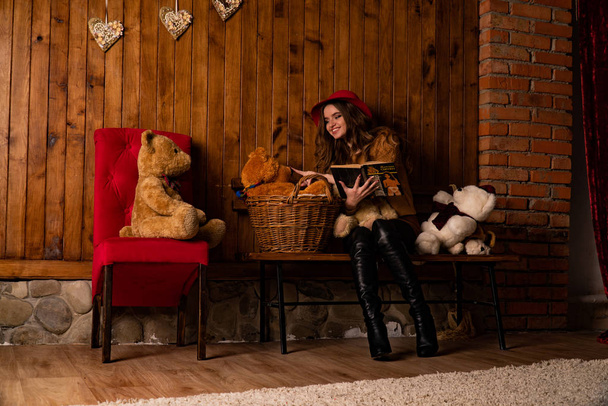 красивая женщина с книгой позирует среди игрушек в студии  - Фото, изображение