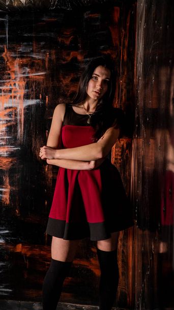 Досить молода сексуальна модель жінка з темним волоссям у червоній сукні позує в темній студії
. - Фото, зображення