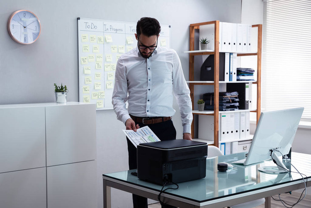 Photo Of Young Businessman Using Printer In Office - Zdjęcie, obraz
