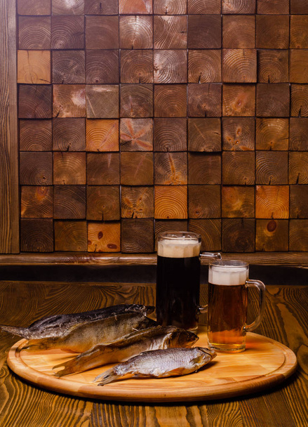 Beer glass with beer on a background of dried fish on a wooden table in a rustic style. - 写真・画像