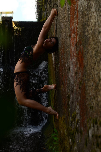 Young brunette model posing against a waterfall - Fotó, kép