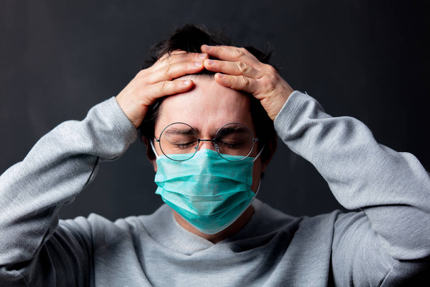 young white man in glasses and protective mask with a headache - Foto, imagen