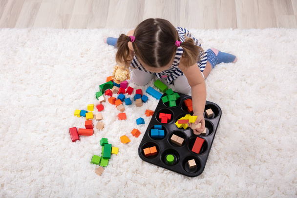 Elevated View Of Girl Sitting On Carpet Playing With Colorful Blocks At Home - Foto, afbeelding