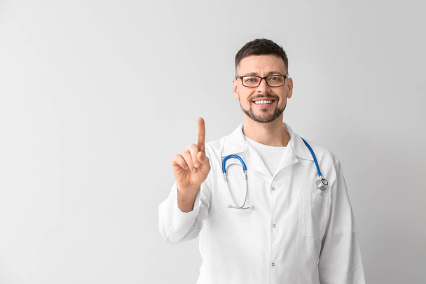 Mężczyzna kardiolog z podniesionym palcem wskazującym na jasnym tle - Zdjęcie, obraz