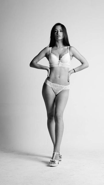 Girl in white lingerie and high heels posing on white background.  - Foto, imagen
