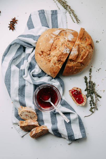 Gresini with thyme in Flatley layout. Slices of white bread on a white background. Raspberry jam with a towel.  - Foto, imagen