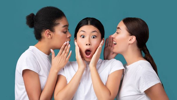 Trois copines partageant des secrets debout sur fond turquoise dans Studio
 - Photo, image