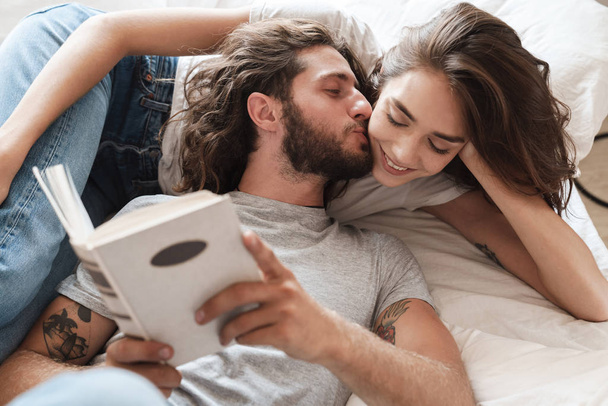 Loving couple indoors at home lies reading book together. - Foto, Bild