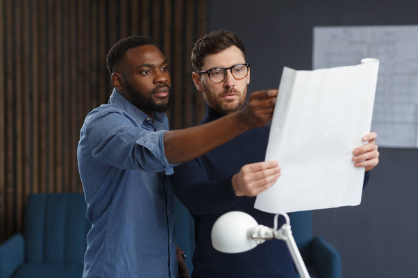 Multiracial engineer team working in office with blue prints and architect equipment sketching,discussing and planning construction project. Partners disputing at work. Business construction concept - Foto, Imagem