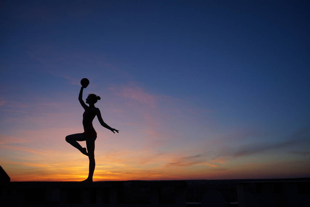 танцівниця в танці робить розгалуження в повітрі проти заходу сонця
. - Фото, зображення
