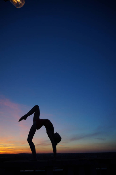 танцівниця в танці робить дроблення в повітрі проти заходу сонця/
 - Фото, зображення