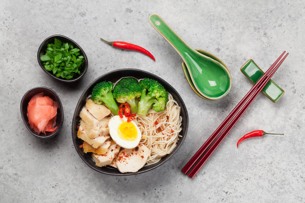 Asian noodle ramen soup with chicken, vegetables and eggs on stone background. Top view flat lay - Photo, Image
