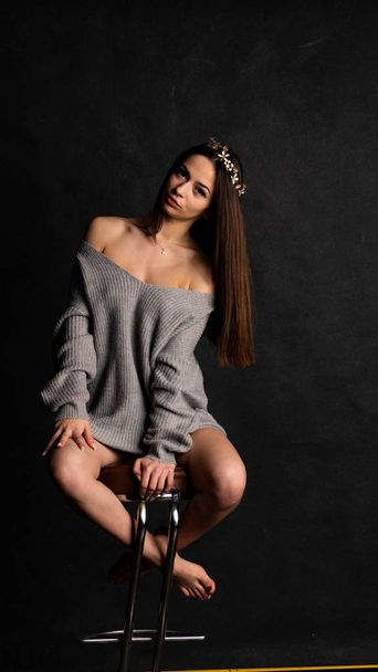 beautiful sexy girl, posing a short gray dress, black background chair - Fotó, kép