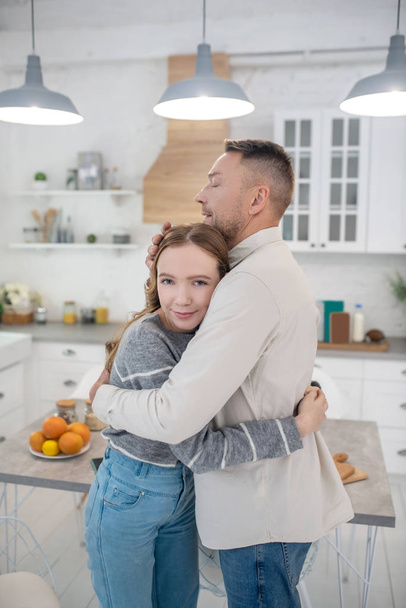 Father and daughter are in the kitchen and hugging. - Fotó, kép