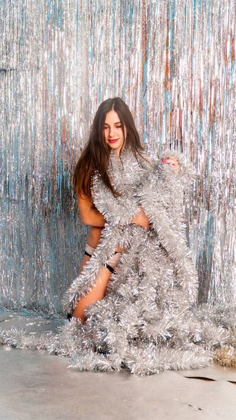 beautiful sexy woman in shiny christmas tinsel posing in studio, holiday concept    - 写真・画像